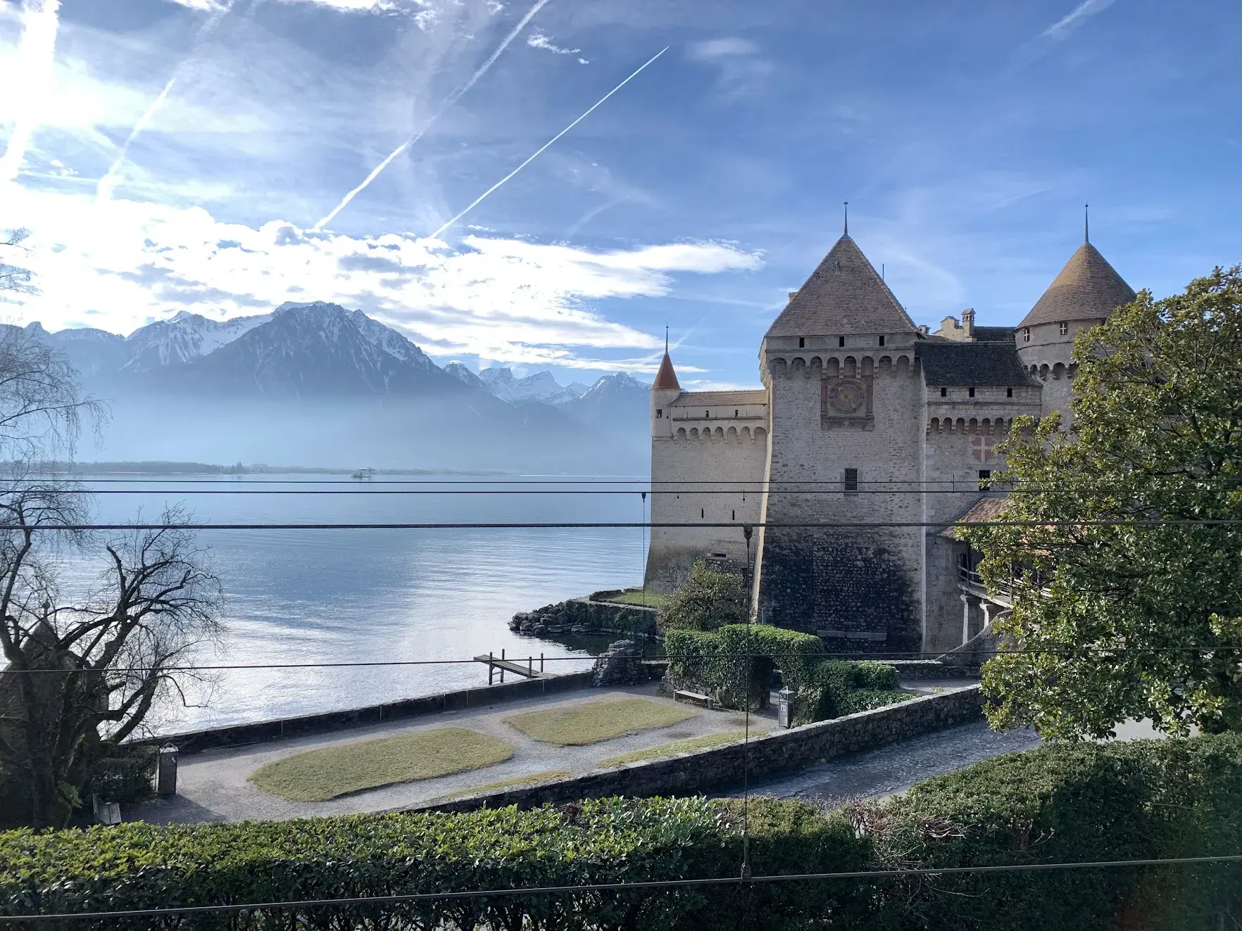 Chillon Castle on the shore of Lake Geneva, with snowy mountains across the water