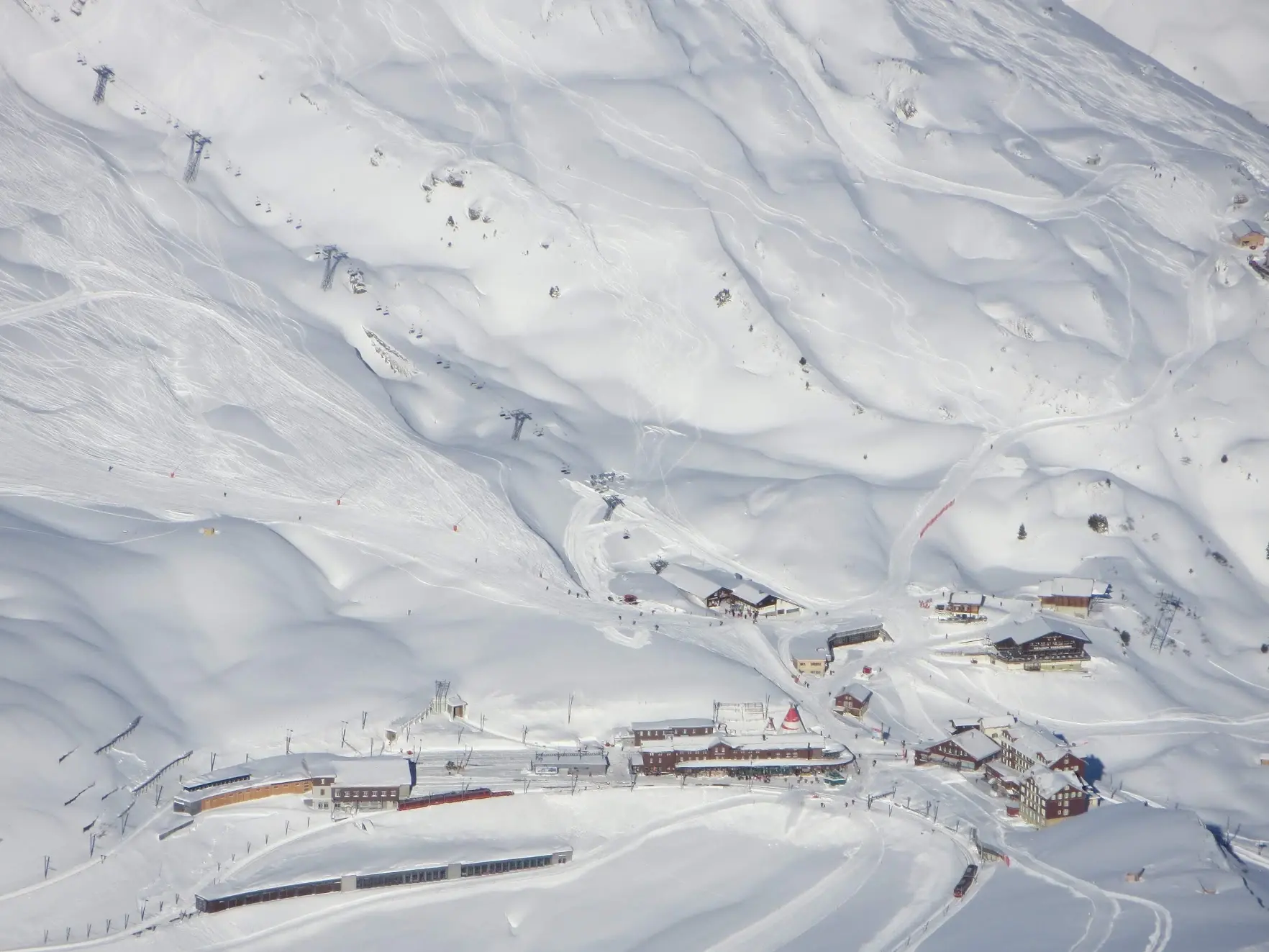 Kleine Scheidegg seen from far above: the railway station, hotels and ski lifts in deep snow