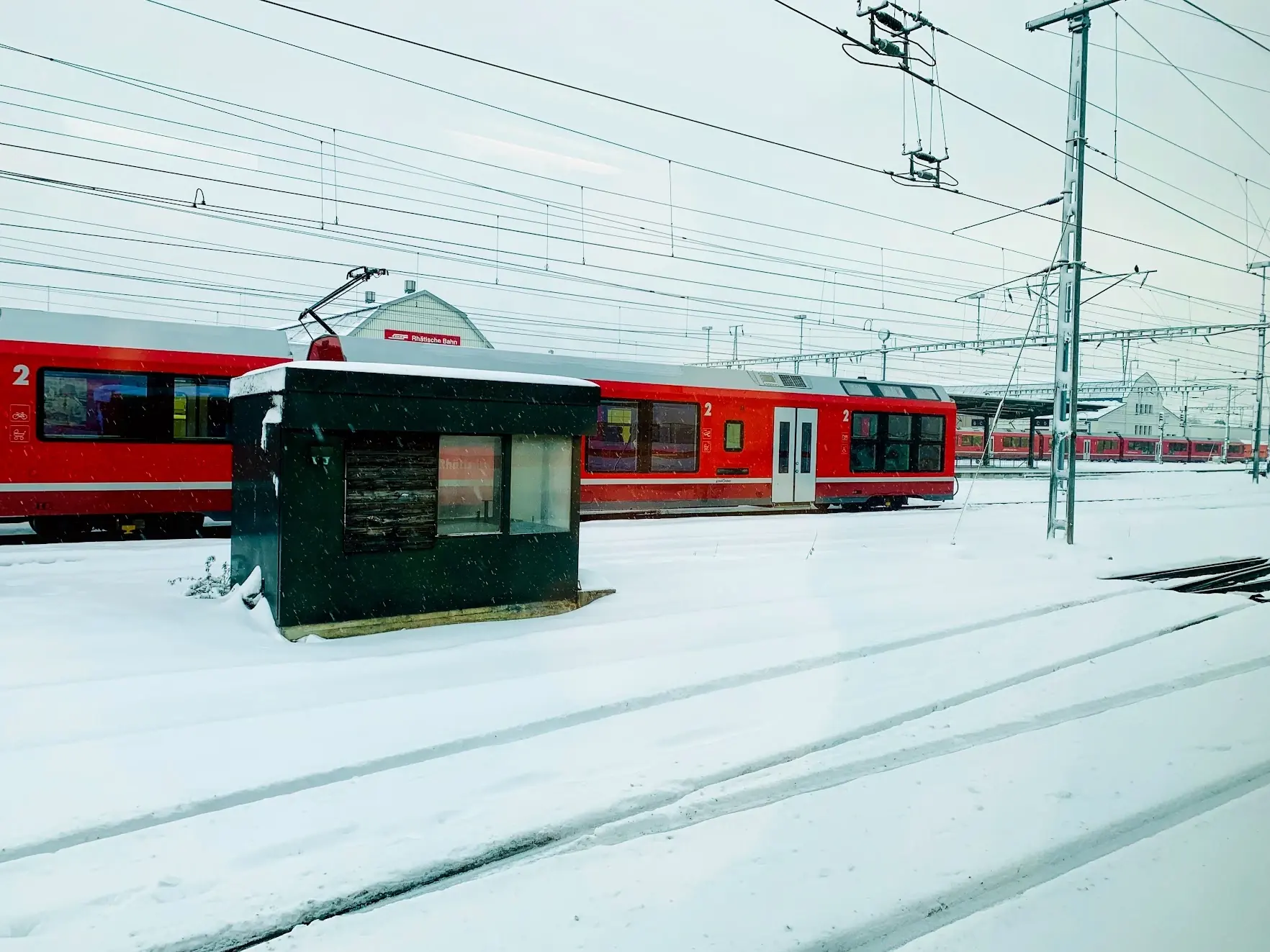 A red Rhaetian Railway train in a snow-covered station