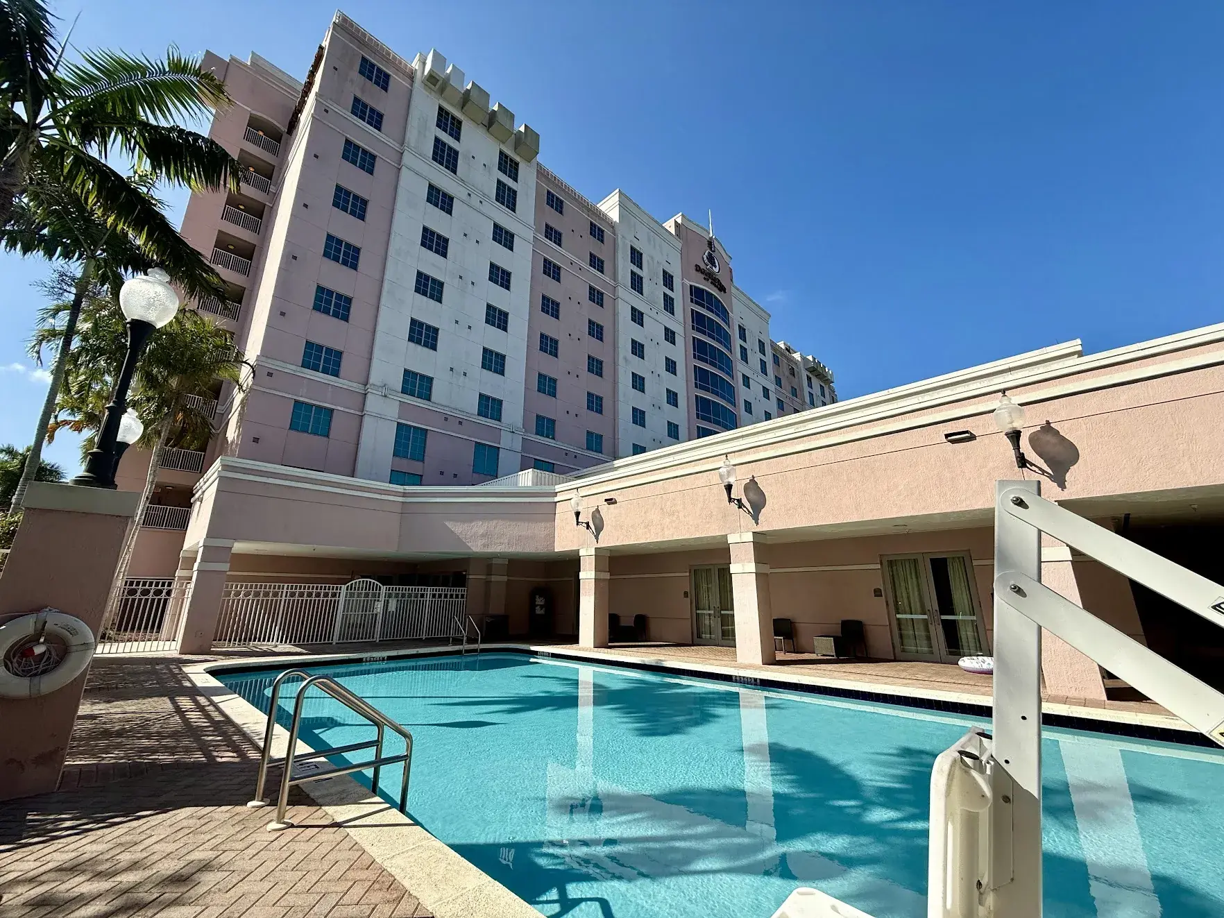The outdoor pool at the DoubleTree by Hilton Sunrise, with a pool lift in the foreground and the pink hotel tower behind