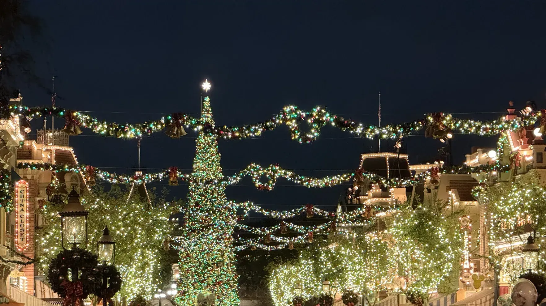 Main Street, U.S.A. at night with a giant lit Christmas tree and garlands of lights