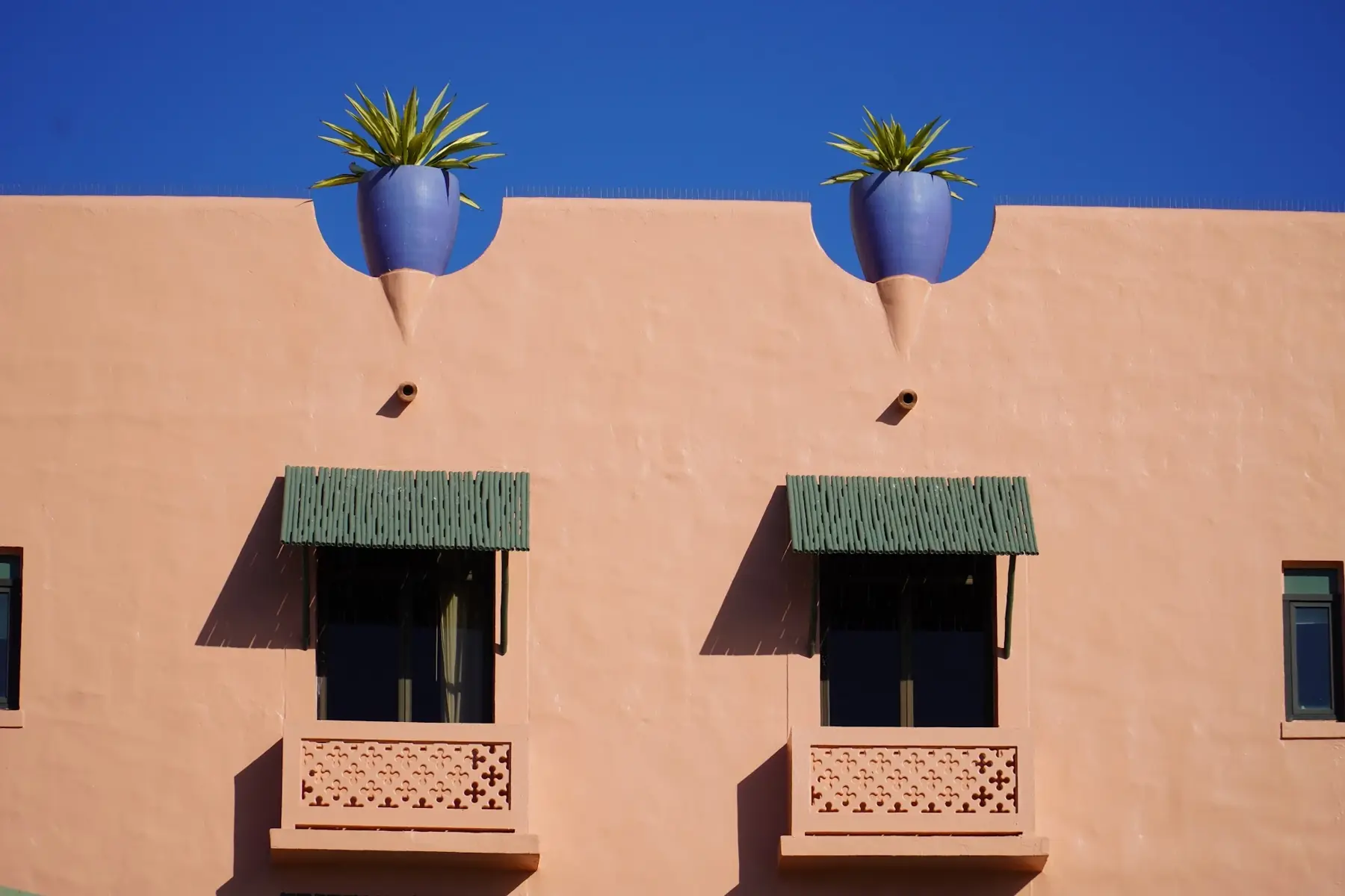 Detail of the Royal Hawaiian pink facade with blue planters and green window awnings